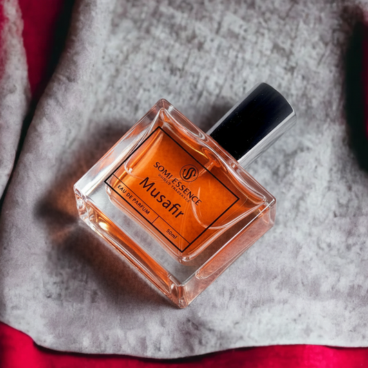 Perfume bottle labeled 'Musafir' by 'Some Essence' on a textured surface with red fabric.